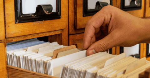 A hand holding a card inside a card catalogue.